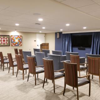 A neatly arranged conference room with chairs facing a television and projector screen.