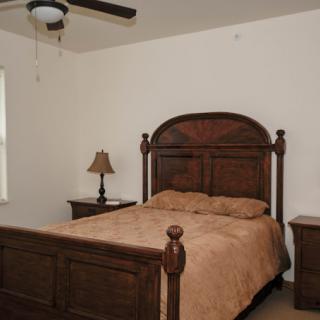 A cozy bedroom with a wooden bed, nightstands, and a ceiling fan.
