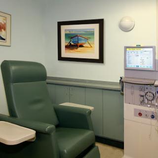 A comfortable patient chair in a medical office, accompanied by healthcare equipment and art on the walls.