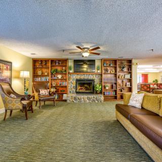 A cozy living room with a fireplace and bookshelves, featuring comfortable seating and warm lighting.
