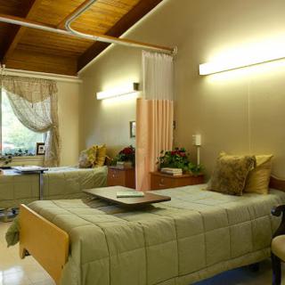 A cozy patient room in a healthcare facility, featuring two beds and warm lighting.