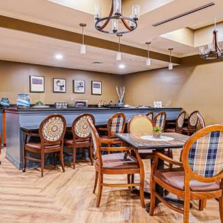 A cozy dining area with elegant chairs and tables, featuring a bar counter and subtle lighting.