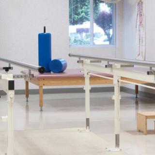 A physical therapy room with parallel bars and exercise equipment.
