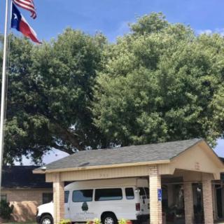 A white van parked in front of a building with flags flying above on a sunny day.