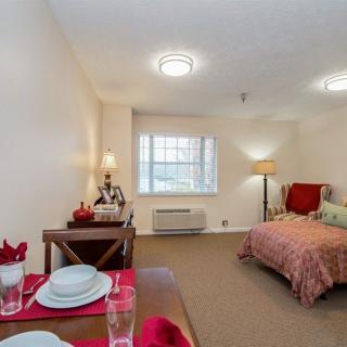 A cozy bedroom with a neatly set table, bed, and soft lighting.