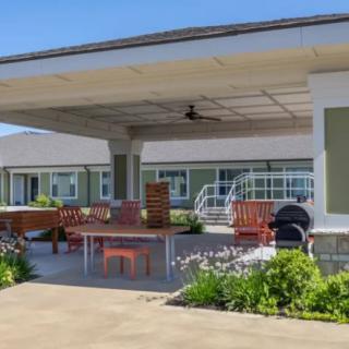 A covered outdoor patio with seating and a garden area under a sunny sky.