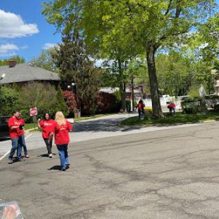 A group of individuals in red shirts engaging in a community event on a sunny day.