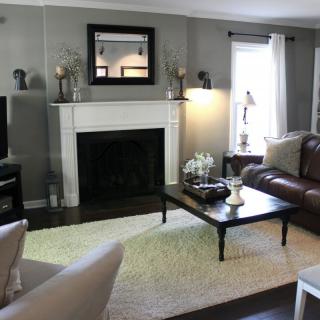 A cozy living room featuring a fireplace, leather sofa, armchair, and a coffee table with decorative items.