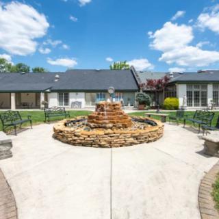 A sunny day in a courtyard with a central fountain and surrounding seating area.