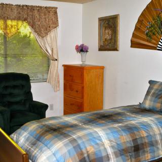 Cozy bedroom with a plaid bedspread, wooden furniture, and a window with curtains.