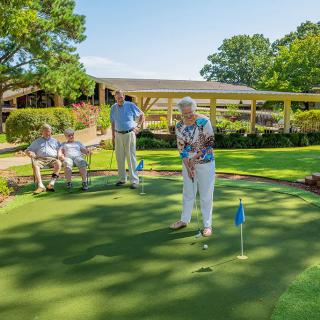 Seniors enjoying a game of golf on a sunny day at the putting green.