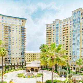 A view of high-rise residential buildings surrounded by palm trees and a courtyard.