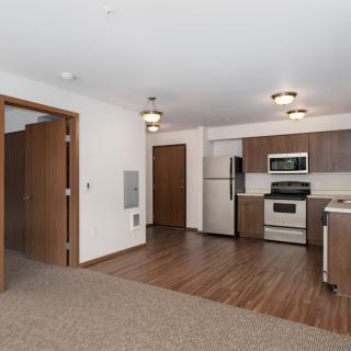 A modern apartment with an open floor plan featuring a kitchen and living area.