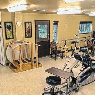 A rehabilitation therapy room equipped with various exercise machines and tools.