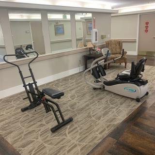 A small indoor gym with exercise equipment including a stationary bike and an elliptical machine.