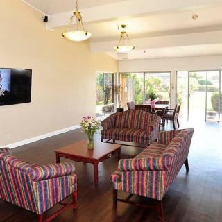 A spacious living room with striped sofas, a coffee table, and a wall-mounted television.