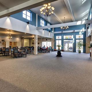 A spacious lobby with elegant chandeliers, seating area, and large windows.