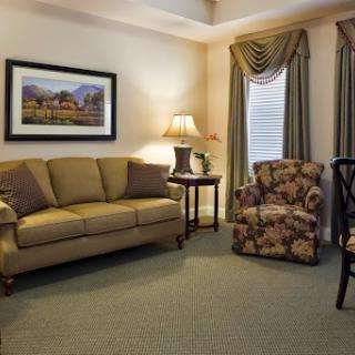 A cozy living room featuring a comfortable sofa, floral armchair, and warm lighting.