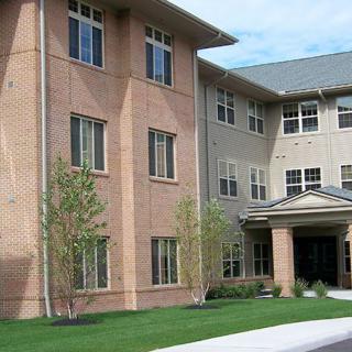 A modern residential apartment building with a landscaped front yard.