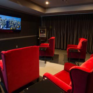 A cozy home theater room with red chairs and a television on the wall.