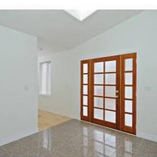 A modern interior with large wooden French doors and glossy flooring.
