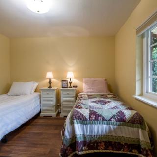 A cozy bedroom with two twin beds, a shared nightstand, and soft lighting from table lamps.