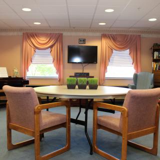 A small conference room with a round meeting table, chairs, and a wall-mounted television.