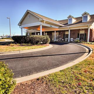 A building with a curved driveway and well-maintained landscaping on a sunny day.