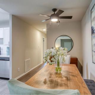 A modern dining area featuring a wooden table, ceiling fan, and a decorative mirror.