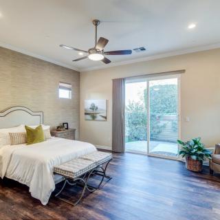 A modern bedroom with hardwood flooring, a ceiling fan, and sliding doors leading to an outdoor space.