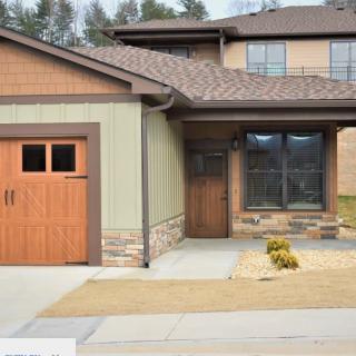 A modern house with a wooden garage door and driveway.