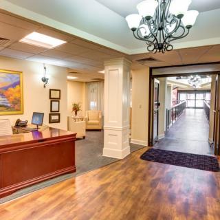 A spacious and elegantly designed reception area with a wooden desk and chandelier lighting.