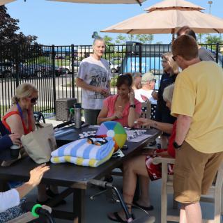 A group of people gathered around a table outdoors on a sunny day.
