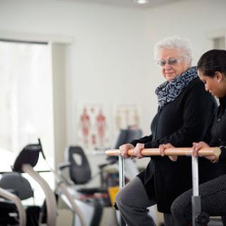 A physical therapist assists an elderly woman during a rehabilitation session, focusing on her mobility and strength.