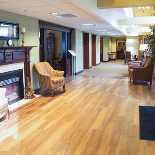 A cozy lobby area featuring a wooden floor, comfortable chairs, and a fireplace.
