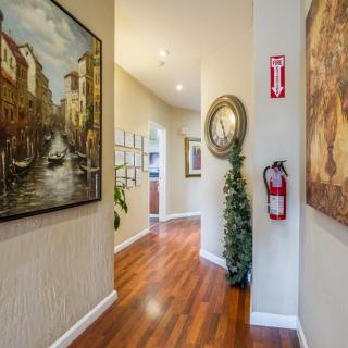 A well-decorated hallway featuring paintings, a fire extinguisher, and a wooden floor.