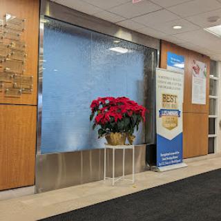 A serene lobby area featuring a water wall and decorative poinsettias, accompanied by an informational banner.