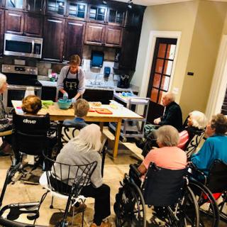 Seniors enjoying a cooking demonstration in a community care facility.