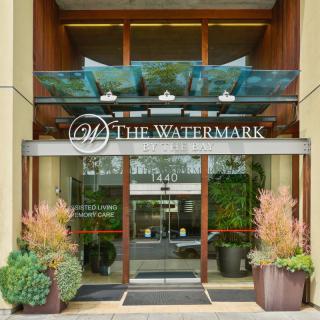 Entrance of The Watermark with glass doors and decorative plants.
