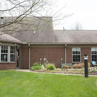 A brick house with a well-maintained lawn and garden in the front yard.