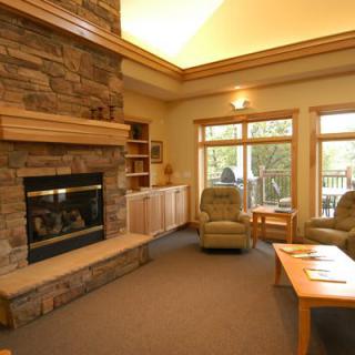 A cozy living room with a stone fireplace and large windows.