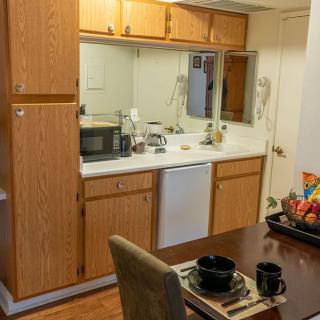 Cozy kitchen and dining area with wooden cabinets, a microwave, and a neatly set table.