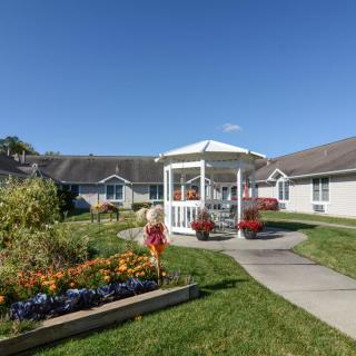 A beautiful garden with a gazebo surrounded by flowers and a pathway on a sunny day.