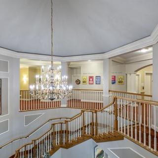 A grand staircase with a chandelier and wall artwork.