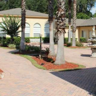A courtyard with palm trees, a fountain, and paved walkways surrounded by light-colored buildings.