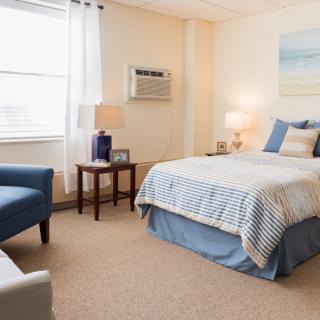 A cozy bedroom with a neatly made bed and comfortable seating.