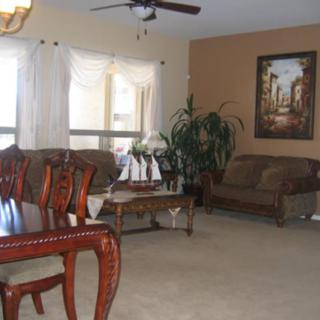A cozy living room with a dining table, sofa, artwork, and indoor plant.