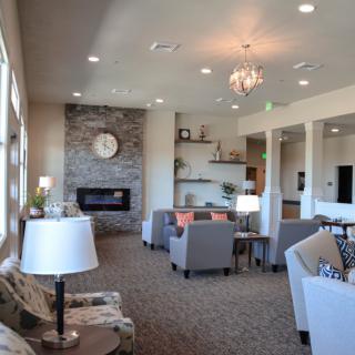 A modern living room with a fireplace, chandelier, and comfortable seating.
