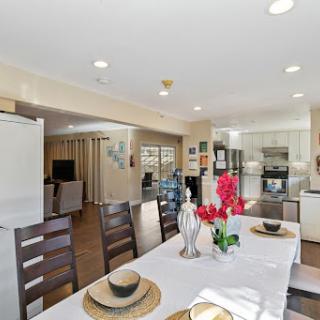 A bright and modern dining area adjacent to a stylish kitchen, featuring a white table set with floral arrangements.