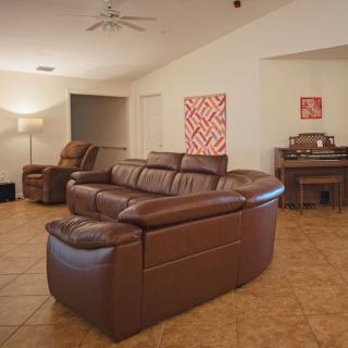 A cozy living room with a large brown leather sofa and a piano.